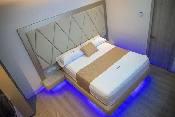 Una cama bien hecha con cabecera, una mesita de noche y un suelo con luz azul.