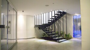 A modern interior with a glass door, a staircase, and a view through a glass door. - Hotel ByHours Circunvalar (Barranquilla)