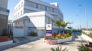 A modern hotel with a white facade, a 'SALIDA' sign, and an 'ENTRADA' sign indicating the entrance. - Hotel ByHours Circunvalar (Barranquilla)