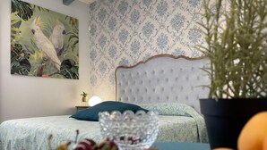 Un dormitorio con una cama, una mesita de noche, una planta en maceta y un frutero.