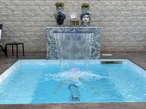 Una piscina con una fuente decorativa, una estatua y una placa con texto.