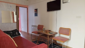 A room with a red sofa, a wicker table with chairs, a television, and a door leading to another room. - Nar Apartment A4 - With sea View Terrace (Pasman)
