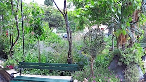 A green bench in a garden with various plants and a stone wall. - Nar Apartment A4 - With sea View Terrace (Pasman)