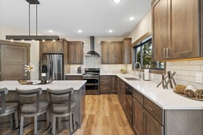 A modern kitchen with wooden cabinets, stainless steel appliances, and a central island with bar stools.