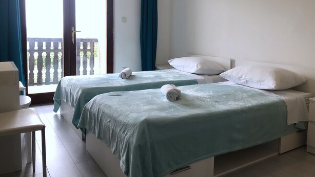 Ein Zimmer mit zwei Betten, einem kleinen Tisch und einem Balkon mit Aussicht.