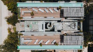 Luchtfoto van een zwembad op een dak, met meerdere ligbedden, een centrale zithoek en een klein rond fonteintje.