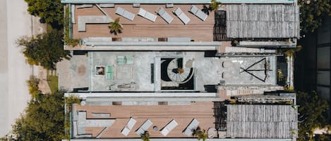An aerial view of a rooftop pool area with multiple lounge chairs, a central seating area, and a small circular fountain.