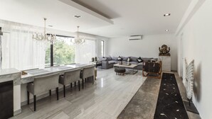 Een moderne keuken met een marmeren aanrecht, grijze gestoffeerde zitmogelijkheden en een kroonluchter.