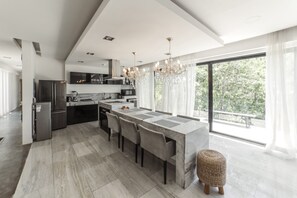 Una cocina moderna con una isla central, electrodomésticos de acero inoxidable y un amplio ventanal con vistas a zonas verdes.