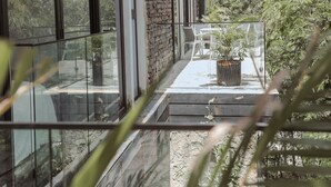 Een modern huis met grote glasramen, een stenen gevel en een balkon met bloempotten.