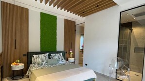 Een moderne slaapkamer met een bed, een nachtkastje, een groene wand en een glazen douche.