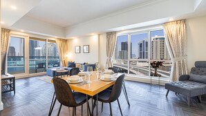 Ein modernes Wohnzimmer mit Essbereich, großen Fenstern mit Vorhängen und Blick auf die Stadt.