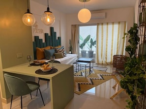 A modern living room with a sofa, a dining area with a table and chairs, and a kitchen area with a counter and a chair. - Modern Studio in San Telmo Design Balcony -309 (Buenos Aires)