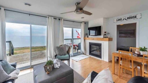 Un salón amplio con chimenea, televisor y vistas a la playa.