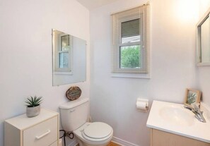 A small, clean bathroom with a toilet, sink, and mirror.