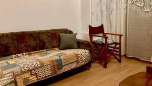 Uma sala de estar com um sofá estampado floral, uma cadeira de madeira e uma cortina padronada.