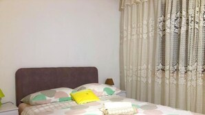 Uma cama bem arrumada com um edredom estampado, um travesseiro e uma toalha enrolada.