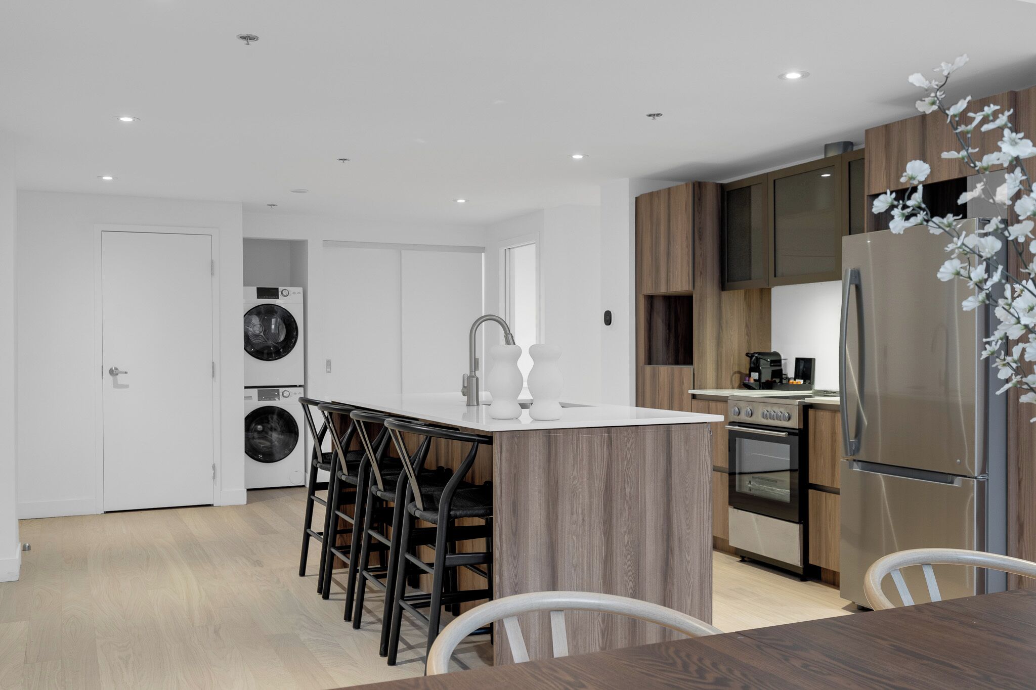 A modern kitchen with a central island, built-in appliances, and a dining area with bar stools.