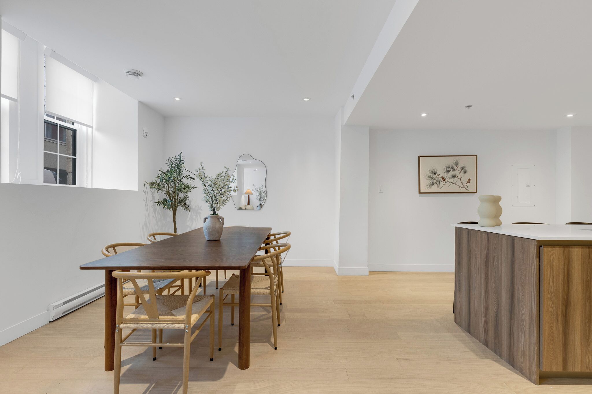 Un comedor moderno con una mesa y sillas de madera, una planta en maceta y una decoración minimalista.
