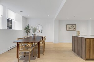 A modern dining area with a wooden table and chairs, a potted plant, and a minimalist decor.