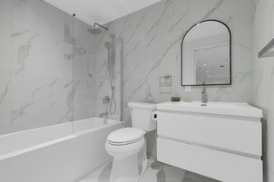 A modern bathroom with a bathtub, toilet, and a large mirror.