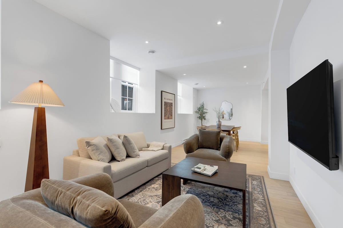 Una sala de estar moderna con un sofá, sillones, una mesa de centro y un televisor.