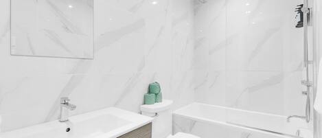 A modern bathroom with a bathtub, toilet, and sink.