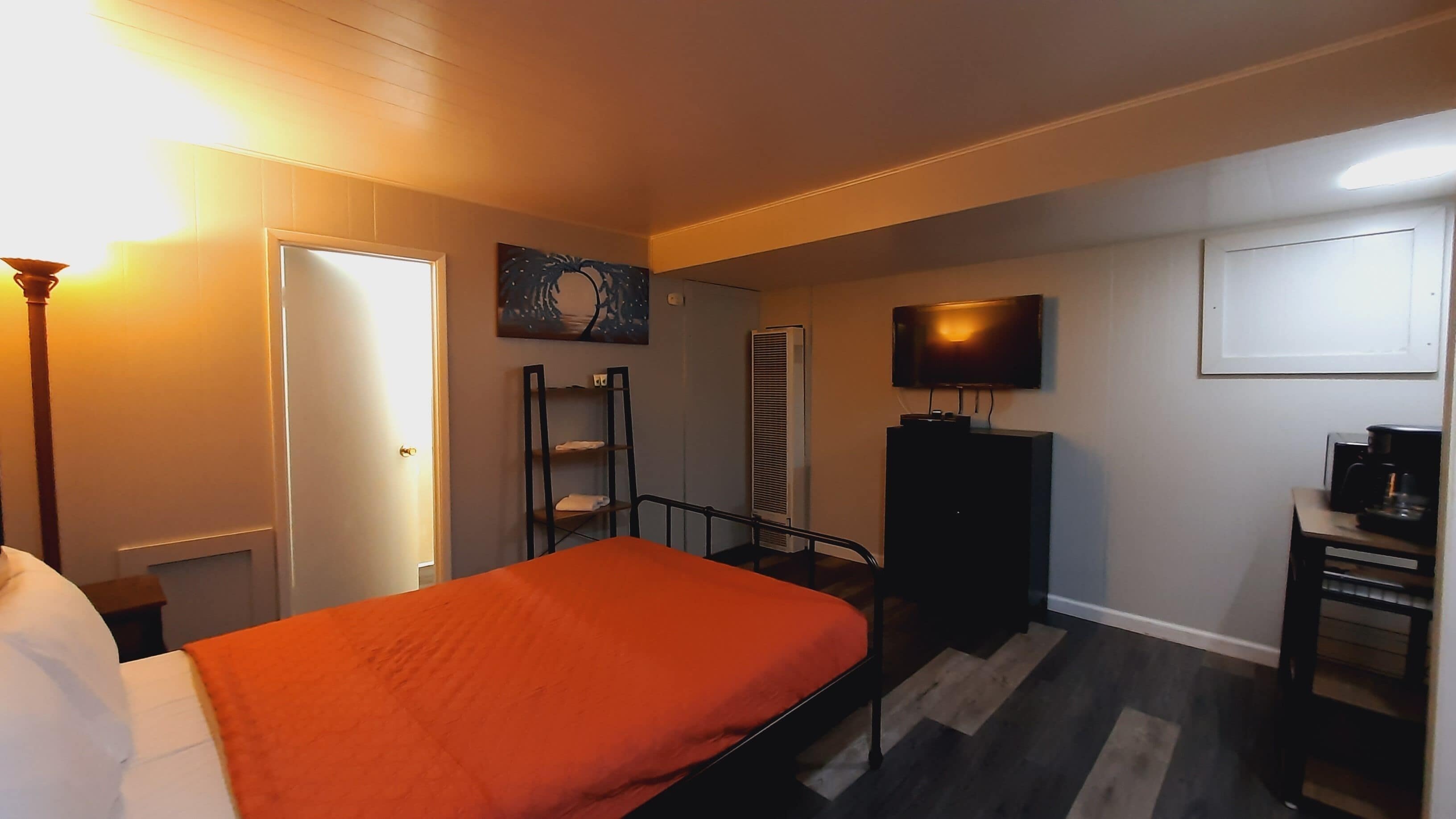 Quarto de hotel com cama, televisão, aquecedor e escrivaninha com máquina de café.