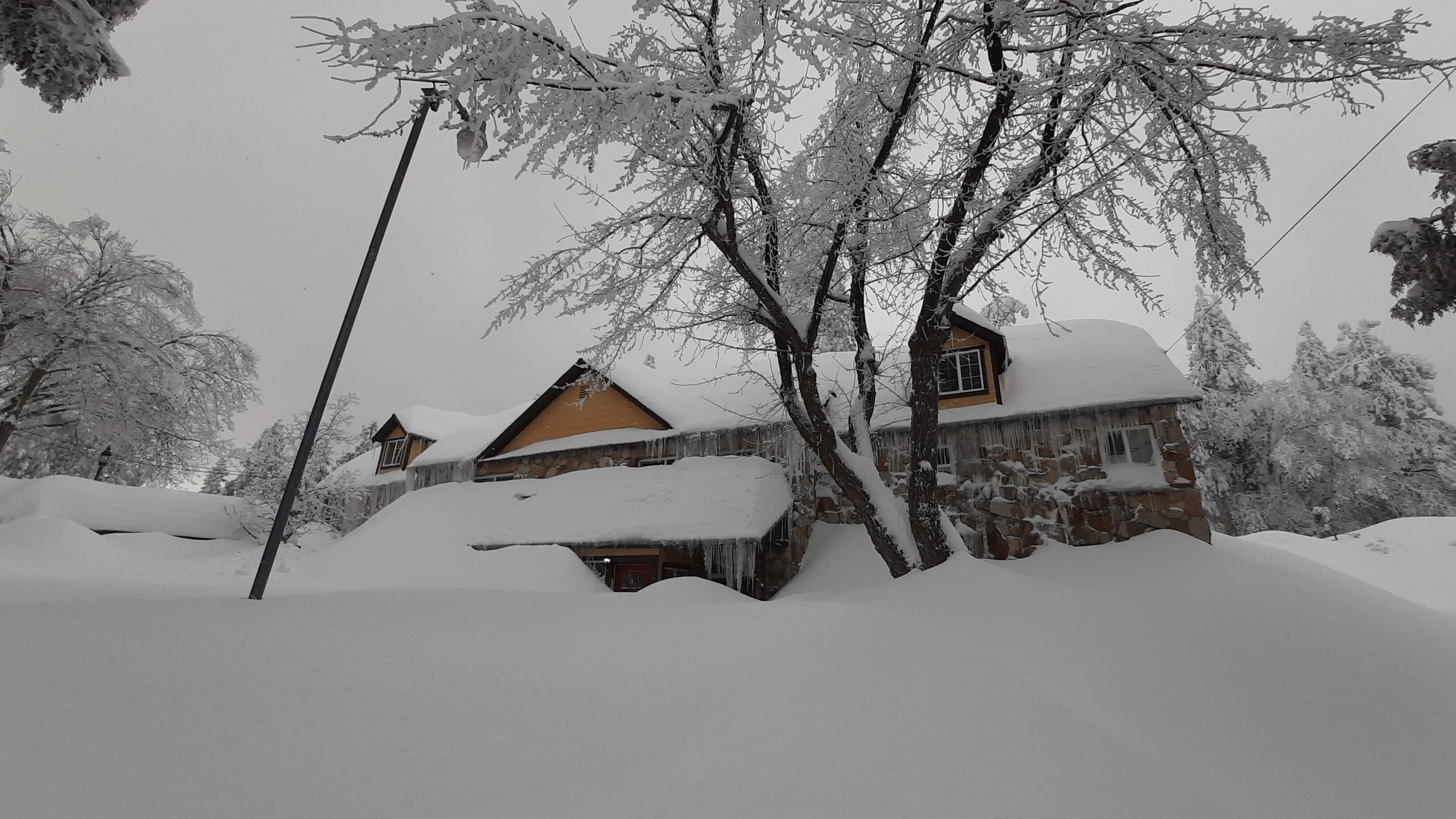 Una casa cubierta de nieve con fachada de piedra y techo de madera.