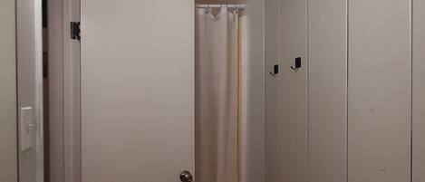 Un baño con un lavabo blanco, cortina de ducha y una puerta que da a un armario.