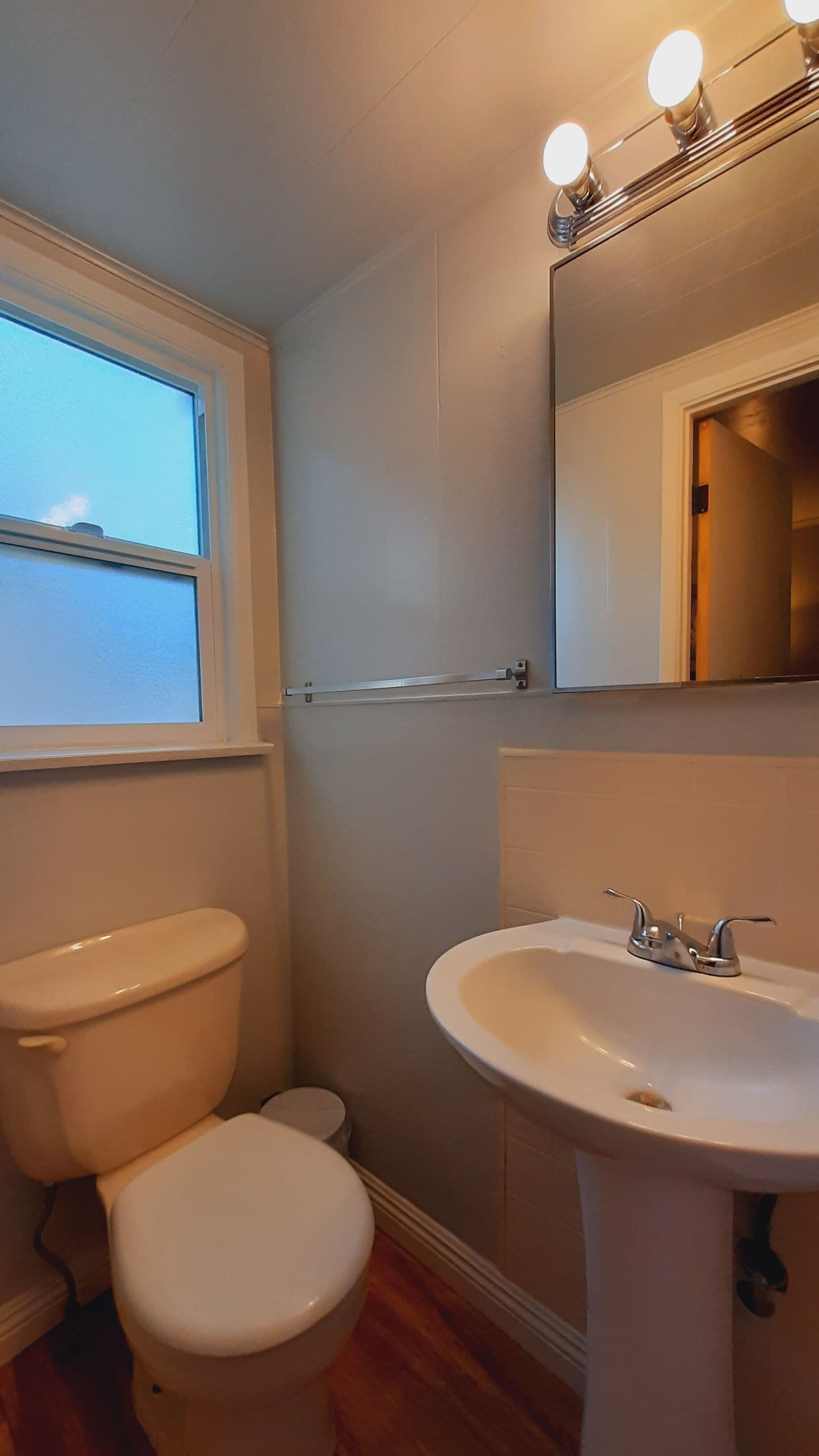 A bathroom with a toilet, sink, and mirror.