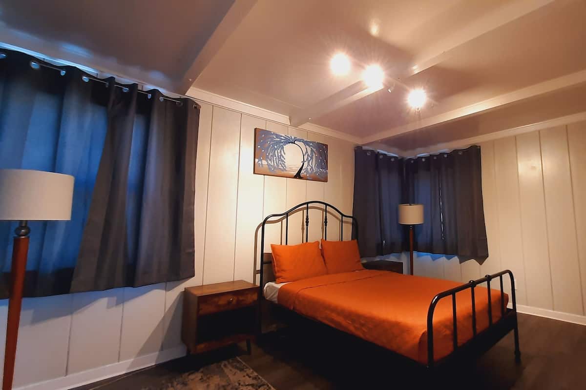 A bedroom with a bed, nightstands, a lamp, and a painting on the wall.