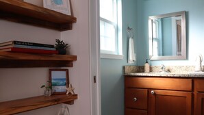 Une salle de bain avec des étagères en bois, un miroir et un plan de toilette muni d’un distributeur de savon.
