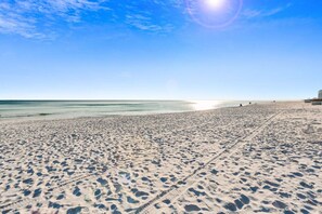 Una extensa playa de arena con huellas y cielo despejado.