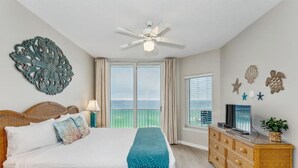 A bedroom with a bed, a ceiling fan, a dresser, a TV, and decorative wall art. - Serenity Now: 9th Floor Summerwind West Condo Located Directly on the Gulf! (Navarre)