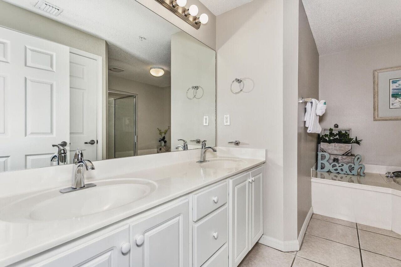A bathroom with a large mirror, two sinks, and a bathtub.