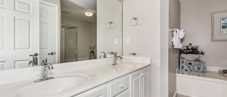 A bathroom with a large mirror, two sinks, and a bathtub.