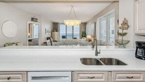A modern kitchen with a large island, stainless steel sink, and a chandelier. - Serenity Now: 9th Floor Summerwind West Condo Located Directly on the Gulf! (Navarre)