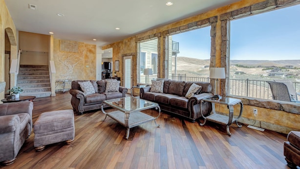 A spacious living room with leather sofas, a glass coffee table, and large windows offering a view of the hills. - Luxury Home with Epic Views - Game Rooms, Gym, Near Leavenworth &
Lake Chelan (Wenatchee)
