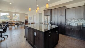 A modern kitchen with dark cabinetry, a central island, and pendant lighting. - Luxury Home with Epic Views - Game Rooms, Gym, Near Leavenworth &
Lake Chelan (Wenatchee)
