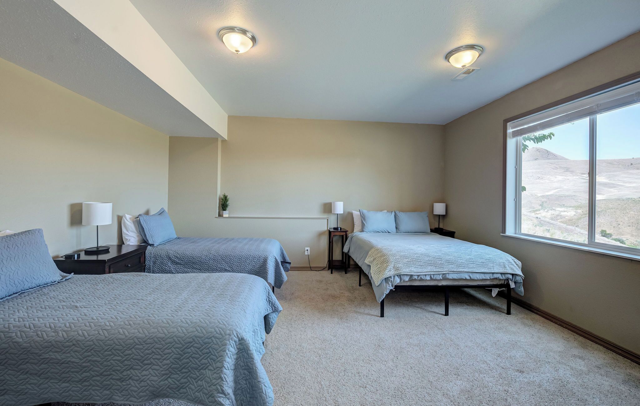 Hotellihuone, jossa on kaksi sänkyä, suuri ikkuna ja näkymä aavikolle.