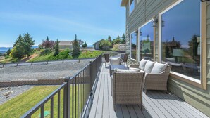 A deck with wicker furniture and a view of the surrounding landscape. - Luxury Home with Epic Views - Game Rooms, Gym, Near Leavenworth &
Lake Chelan (Wenatchee)
