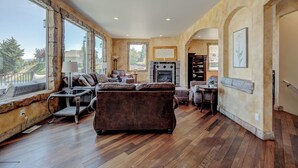 A spacious living room with a fireplace, large windows, and a view of the outdoors. - Luxury Home with Epic Views - Game Rooms, Gym, Near Leavenworth &
Lake Chelan (Wenatchee)