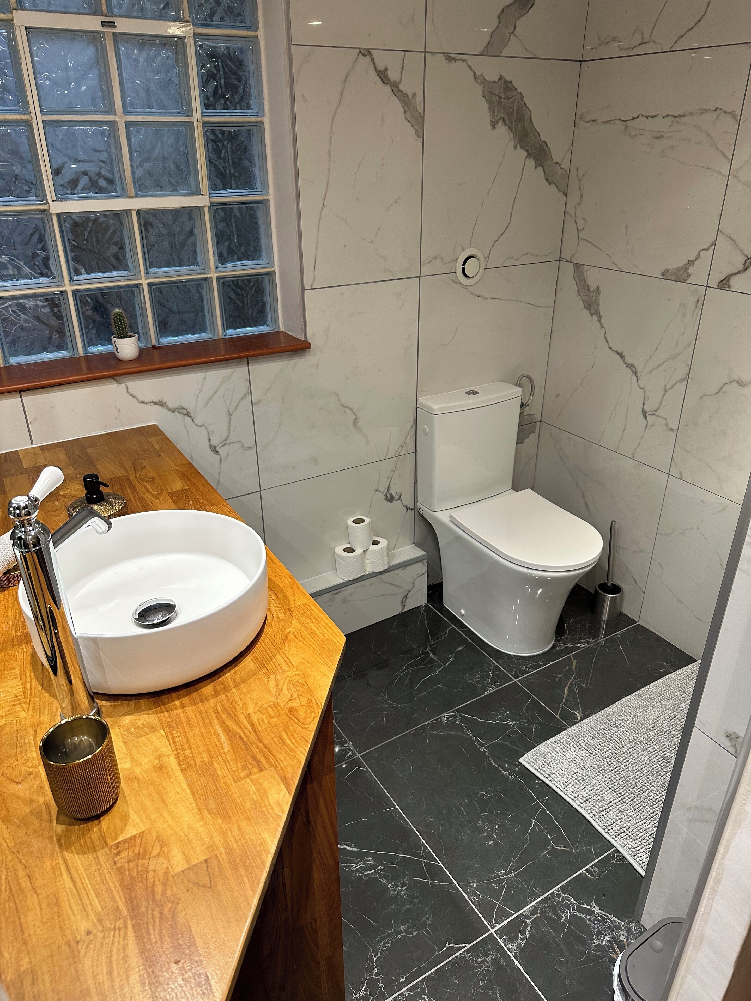 Un baño con tocador de madera, lavamanos blanco y un inodoro.