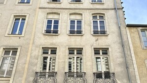 A multi-story building with a classic architectural style, featuring arched windows and decorative iron railings on the balconies.