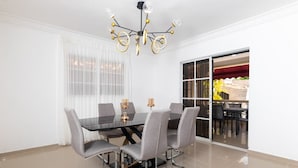 Un coin repas avec une table noire, des chaises grises et un lustre.