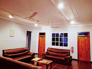 A living room with two leather sofas, a coffee table, a ceiling fan, and a window with blinds. - Room-renajoe Ejisu-kubease (Kubease)