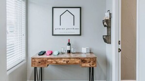 Un escritorio de madera con un cartel enmarcado encima, una botella de vino y varios objetos sobre él.