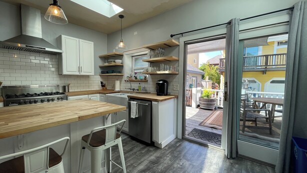 A modern kitchen with a wooden countertop, stainless steel appliances, and a skylight. - Sunlit Surf House | Downtown | Walk to Beach (Santa Cruz)