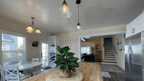 A modern kitchen with a wooden island, pendant lights, and a stainless steel refrigerator. - Sunlit Surf House | Downtown | Walk to Beach (Santa Cruz)